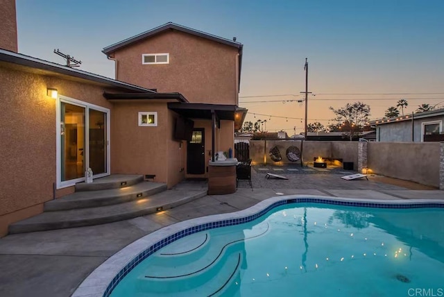 pool at dusk featuring a patio area