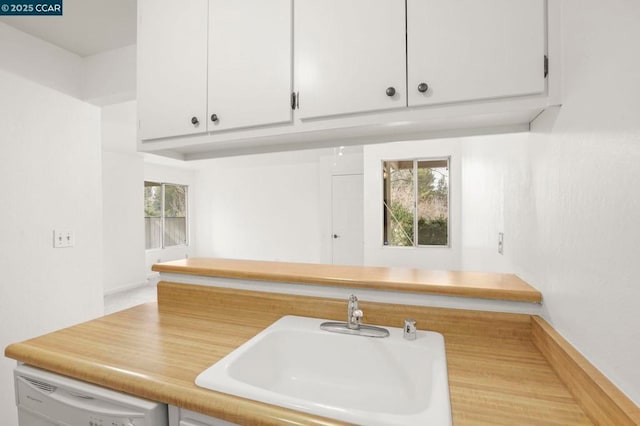 kitchen with white cabinetry, sink, and white dishwasher