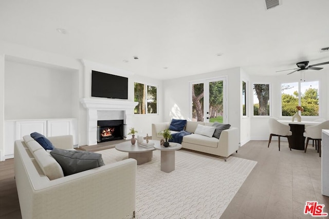 living room with french doors, ceiling fan, and light wood-type flooring