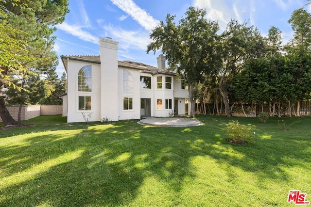 back of property with a yard and a patio