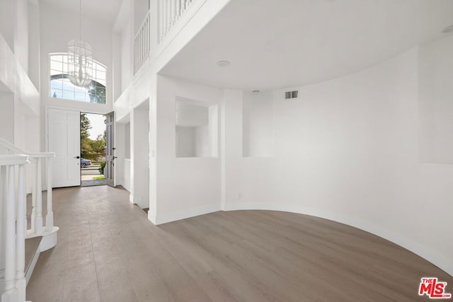 entrance foyer with hardwood / wood-style floors, a chandelier, and a high ceiling