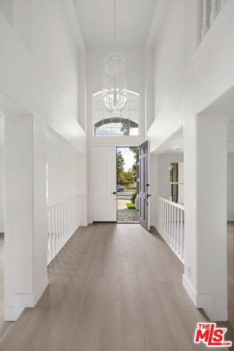 entrance foyer with hardwood / wood-style flooring, a notable chandelier, and a high ceiling