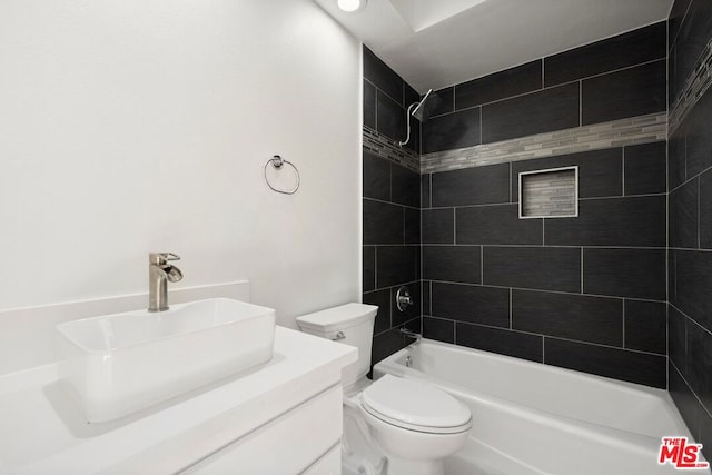 full bathroom featuring vanity, tiled shower / bath combo, and toilet