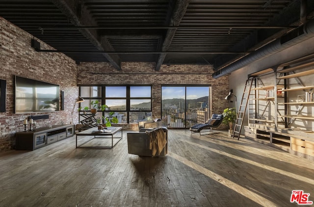 interior space featuring hardwood / wood-style flooring, a high ceiling, and brick wall