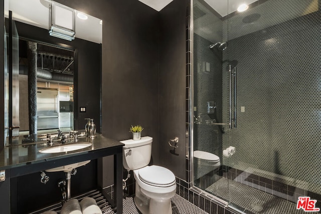 bathroom featuring sink, a tile shower, and toilet