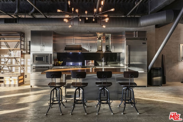 kitchen with built in appliances, sink, and a kitchen breakfast bar