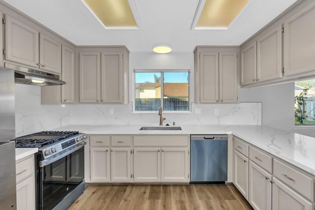 kitchen with light stone counters, appliances with stainless steel finishes, sink, and backsplash