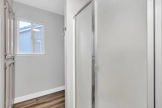 bathroom with wood-type flooring and a shower with shower door