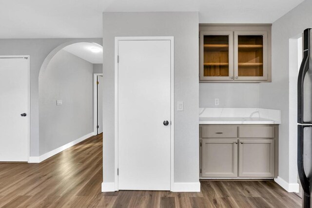 kitchen with dark hardwood / wood-style floors, black refrigerator, and gray cabinetry