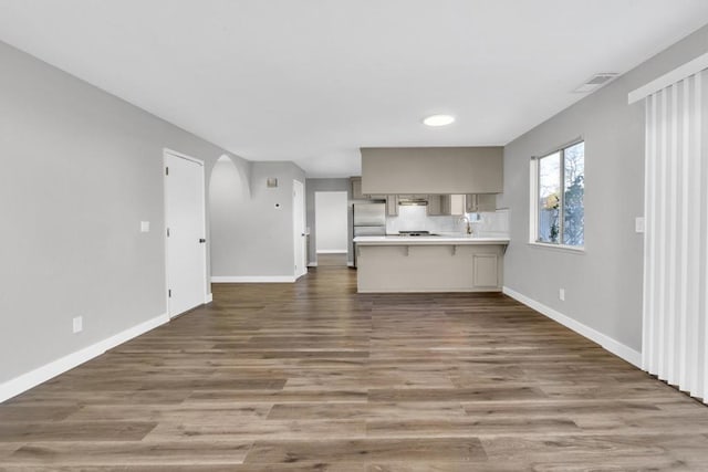 unfurnished living room featuring sink and dark hardwood / wood-style flooring