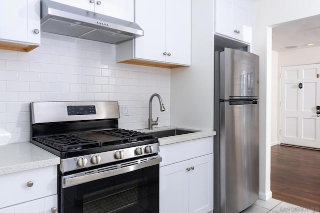 kitchen with sink, light stone counters, stainless steel appliances, decorative backsplash, and white cabinets