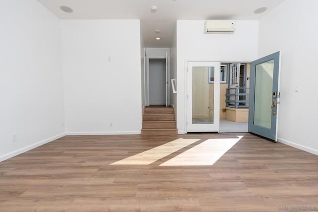 empty room with an AC wall unit, hardwood / wood-style floors, and french doors