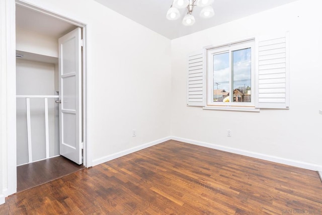 unfurnished bedroom with dark hardwood / wood-style floors and a chandelier