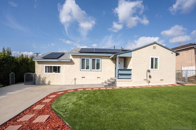 rear view of property featuring a lawn and solar panels