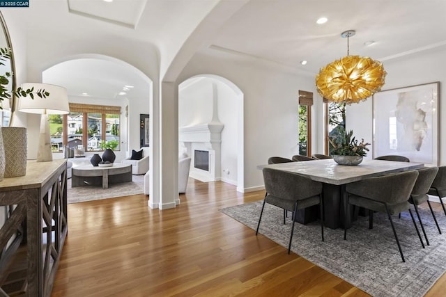 dining space with a chandelier, hardwood / wood-style floors, and a fireplace