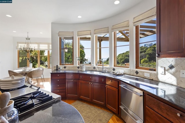 kitchen with pendant lighting, dishwasher, sink, a chandelier, and decorative backsplash