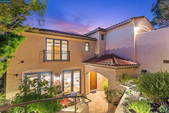 back house at dusk featuring a patio area and french doors