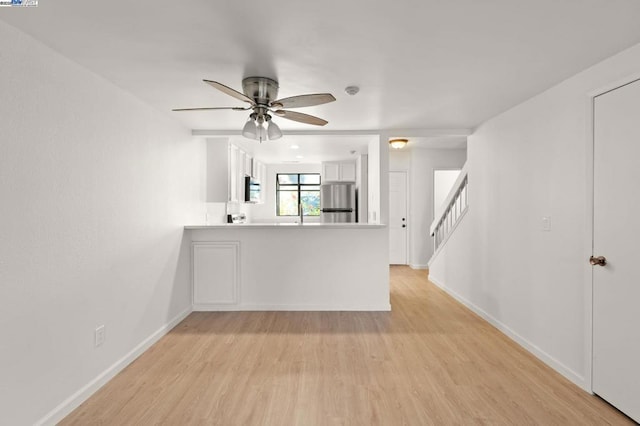 interior space featuring appliances with stainless steel finishes, white cabinetry, ceiling fan, kitchen peninsula, and light hardwood / wood-style flooring