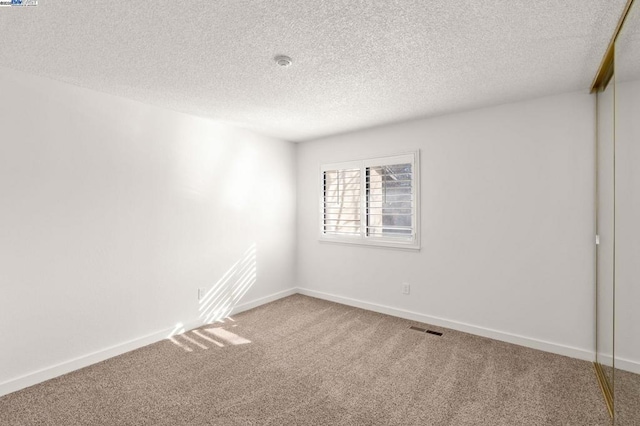 unfurnished room with a textured ceiling and carpet