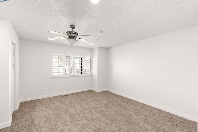 carpeted empty room with a textured ceiling and ceiling fan