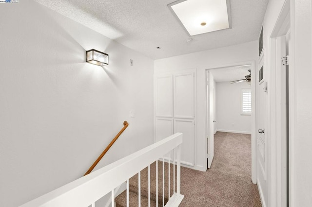 corridor featuring light carpet and a textured ceiling