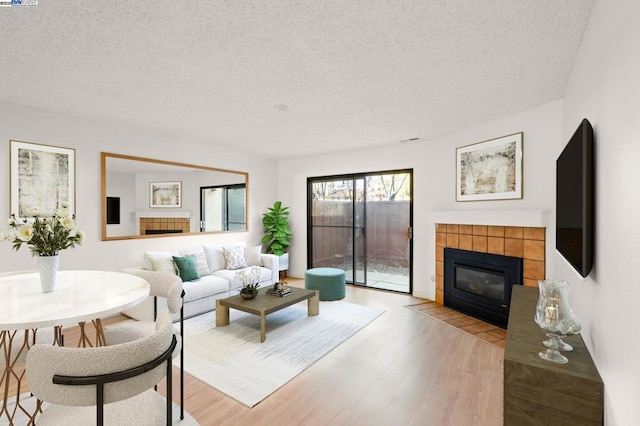 living room featuring a fireplace, light hardwood / wood-style floors, and a textured ceiling