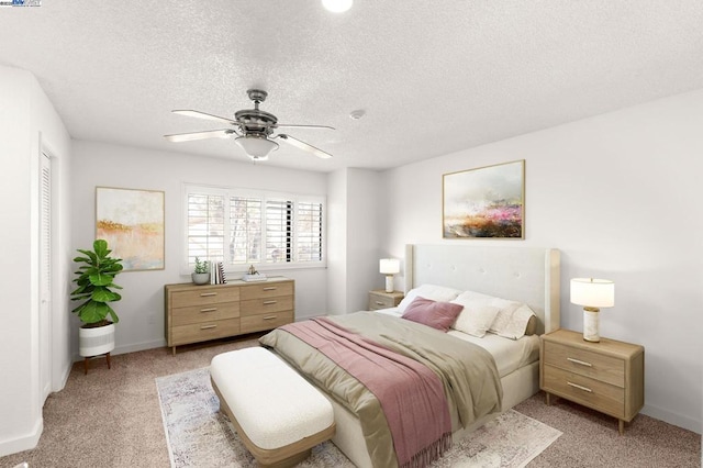 bedroom featuring ceiling fan, light colored carpet, and a textured ceiling