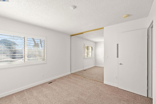 unfurnished bedroom featuring carpet flooring, a closet, and a textured ceiling