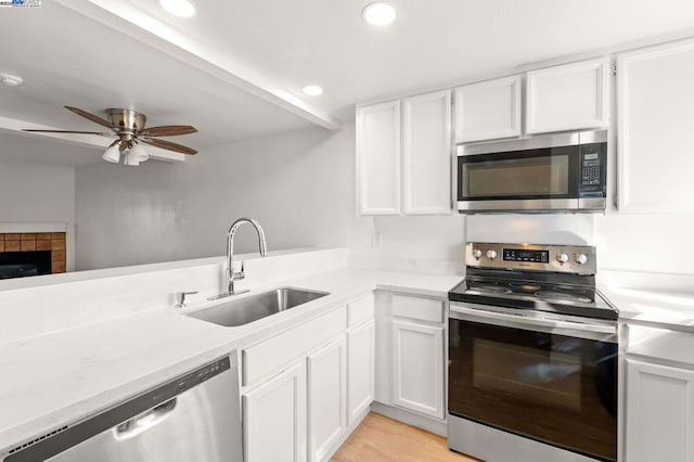 kitchen featuring sink, white cabinets, ceiling fan, stainless steel appliances, and light hardwood / wood-style flooring