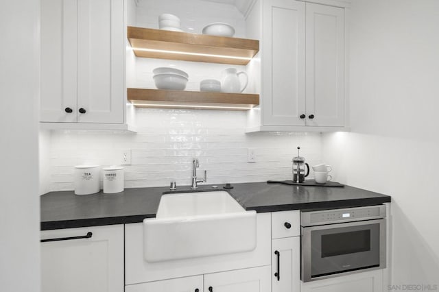 kitchen featuring tasteful backsplash, white cabinetry, sink, and wall oven