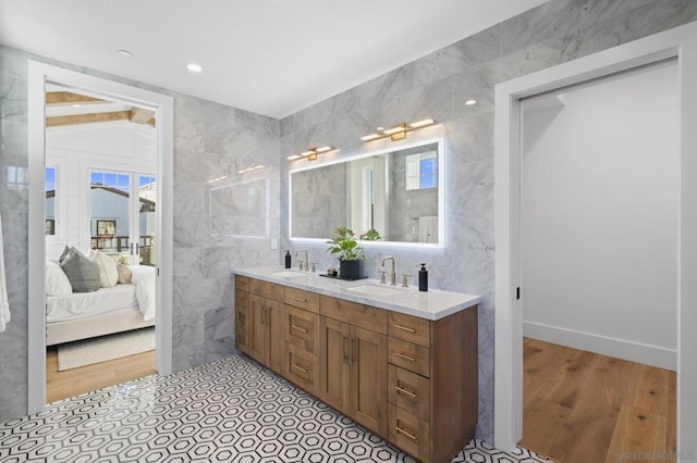 bathroom with wood-type flooring, vaulted ceiling, tile walls, and vanity