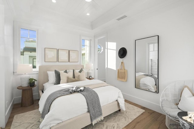 bedroom featuring ornamental molding, a tray ceiling, and light hardwood / wood-style floors