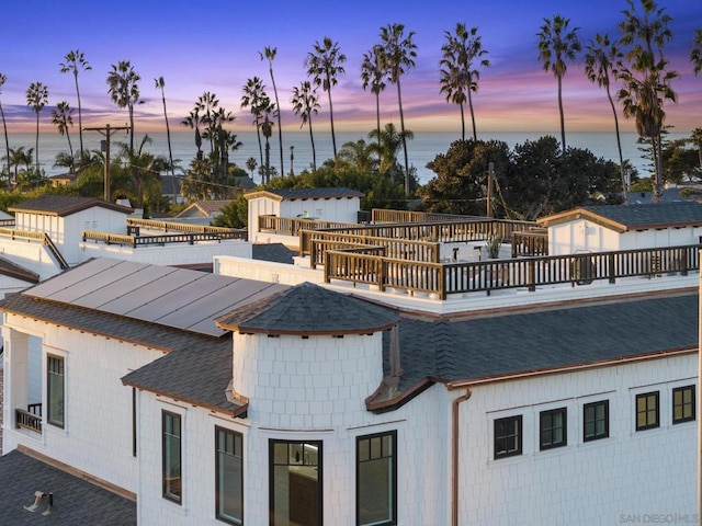 back house at dusk with a balcony and a water view