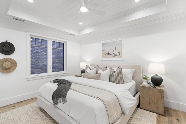 bedroom with a raised ceiling, crown molding, ceiling fan, and light wood-type flooring