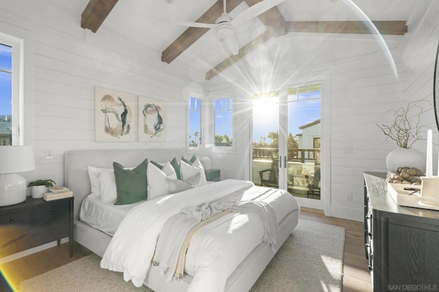 bedroom with ceiling fan, access to exterior, vaulted ceiling with beams, wooden walls, and light wood-type flooring