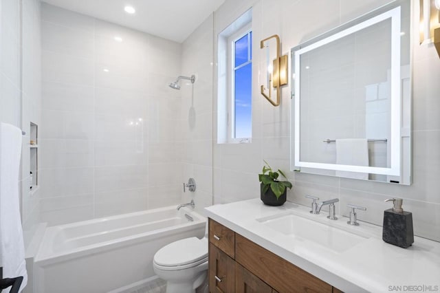 full bathroom featuring tiled shower / bath combo, vanity, tile walls, and toilet