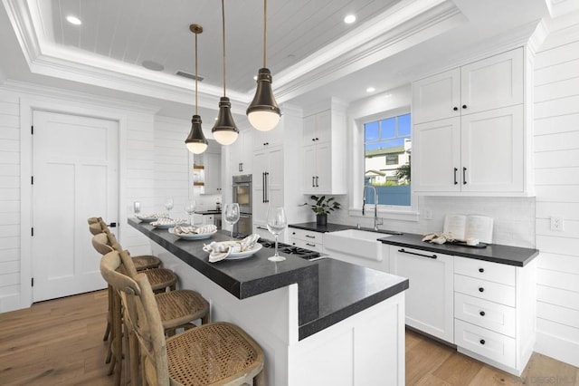 kitchen with a raised ceiling, white cabinetry, a breakfast bar area, and decorative light fixtures