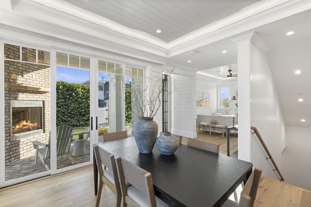 dining space with ornamental molding, a brick fireplace, ceiling fan, and light hardwood / wood-style floors