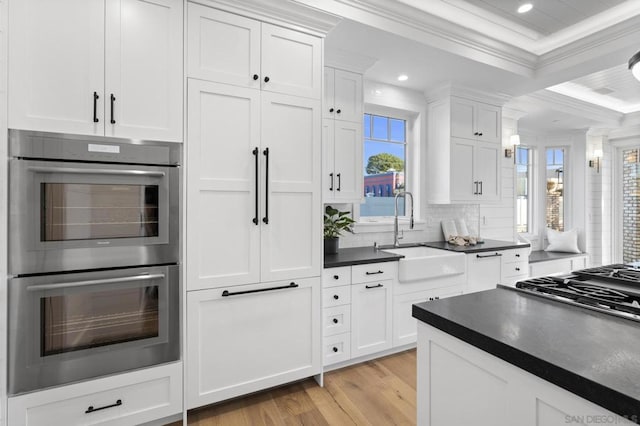 kitchen with sink, light hardwood / wood-style flooring, double oven, ornamental molding, and white cabinets