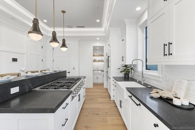 kitchen with white cabinetry, sink, pendant lighting, and light wood-type flooring