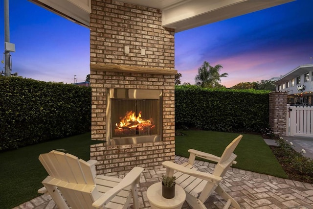 patio terrace at dusk featuring an outdoor brick fireplace