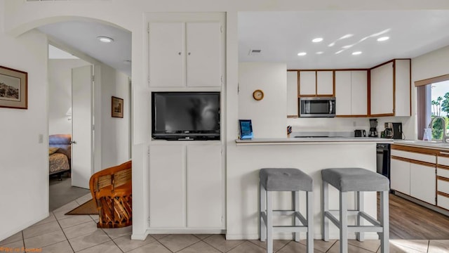 kitchen with white cabinetry, sink, light tile patterned flooring, and a kitchen bar