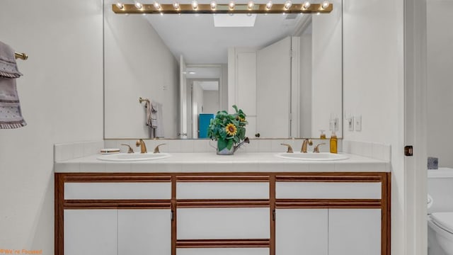 bathroom with a skylight, vanity, and toilet