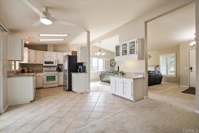 kitchen with pendant lighting, white appliances, vaulted ceiling, and white cabinets