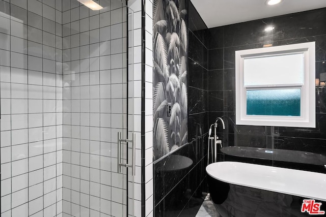 bathroom featuring tile walls and plus walk in shower