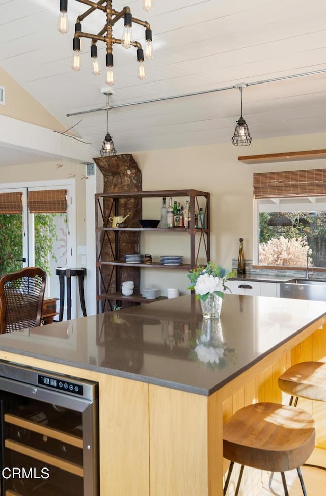 kitchen featuring lofted ceiling, sink, light brown cabinets, pendant lighting, and beverage cooler