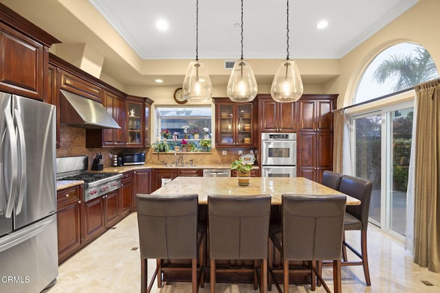 kitchen featuring ventilation hood, sink, a kitchen bar, a center island, and stainless steel appliances