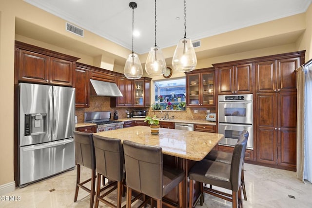 kitchen featuring range hood, stainless steel appliances, light stone counters, a kitchen island, and decorative light fixtures