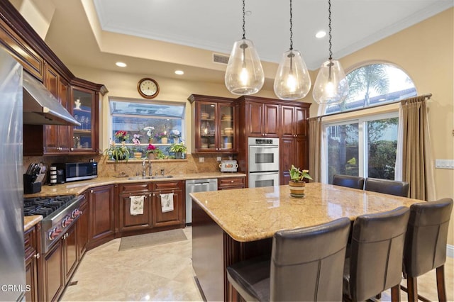 kitchen with stainless steel appliances, sink, a kitchen bar, and decorative backsplash