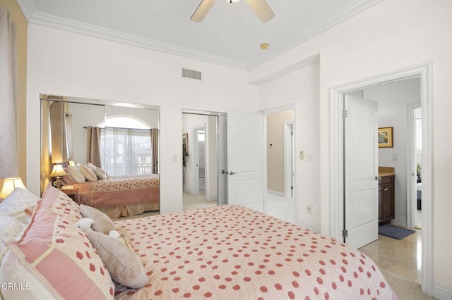 bedroom with crown molding, two closets, ceiling fan, and ensuite bath